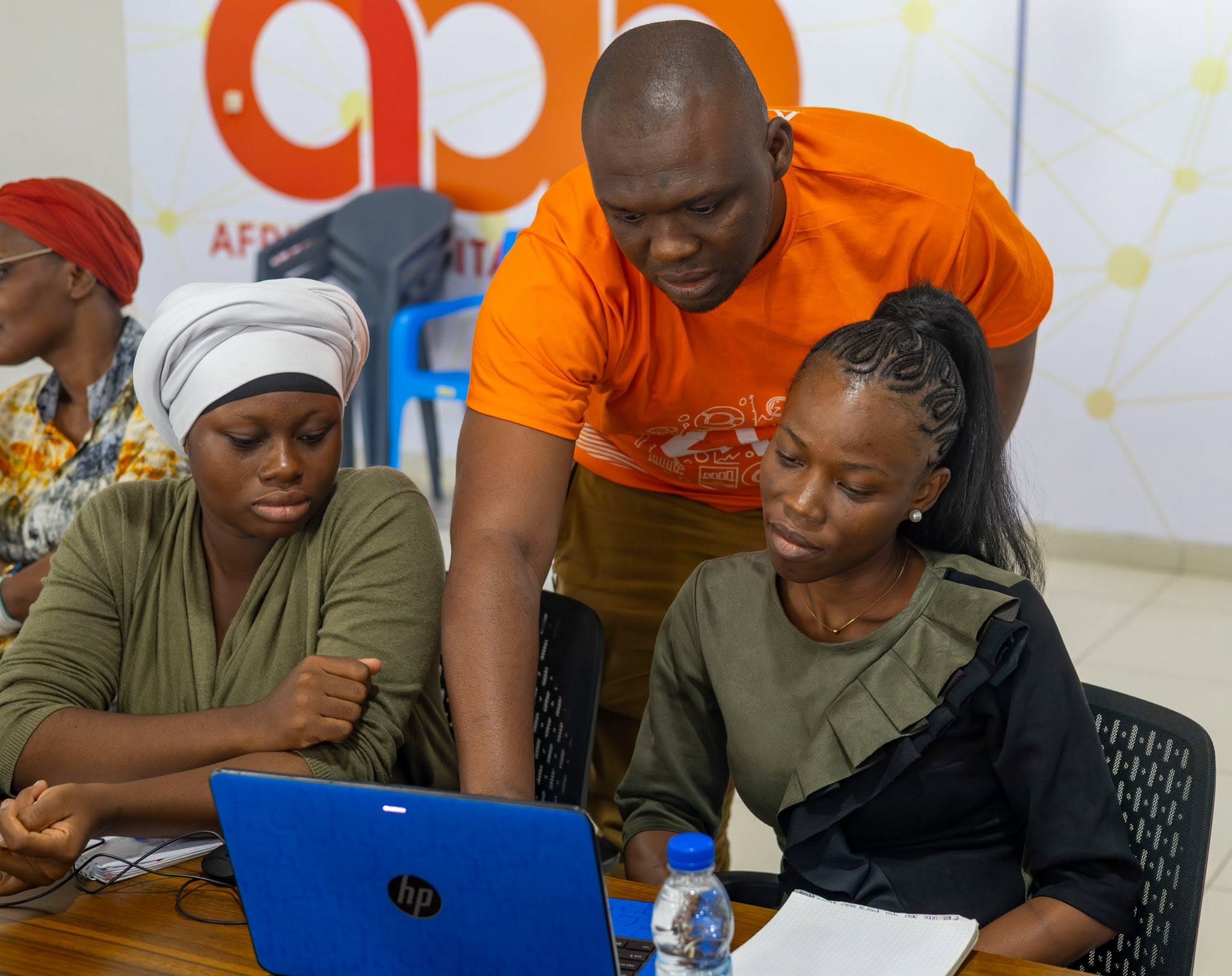 Abdoul Karim Camara aide deux participantes sur un ordinateur